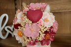 Composition artisanale de bougies en forme de fleurs avec cœur central rouge, présentée dans un élégant contenant blanc. Une création romantique idéale pour un cadeau original, une décoration de mariage ou une attention délicate pour la Saint-Valentin.