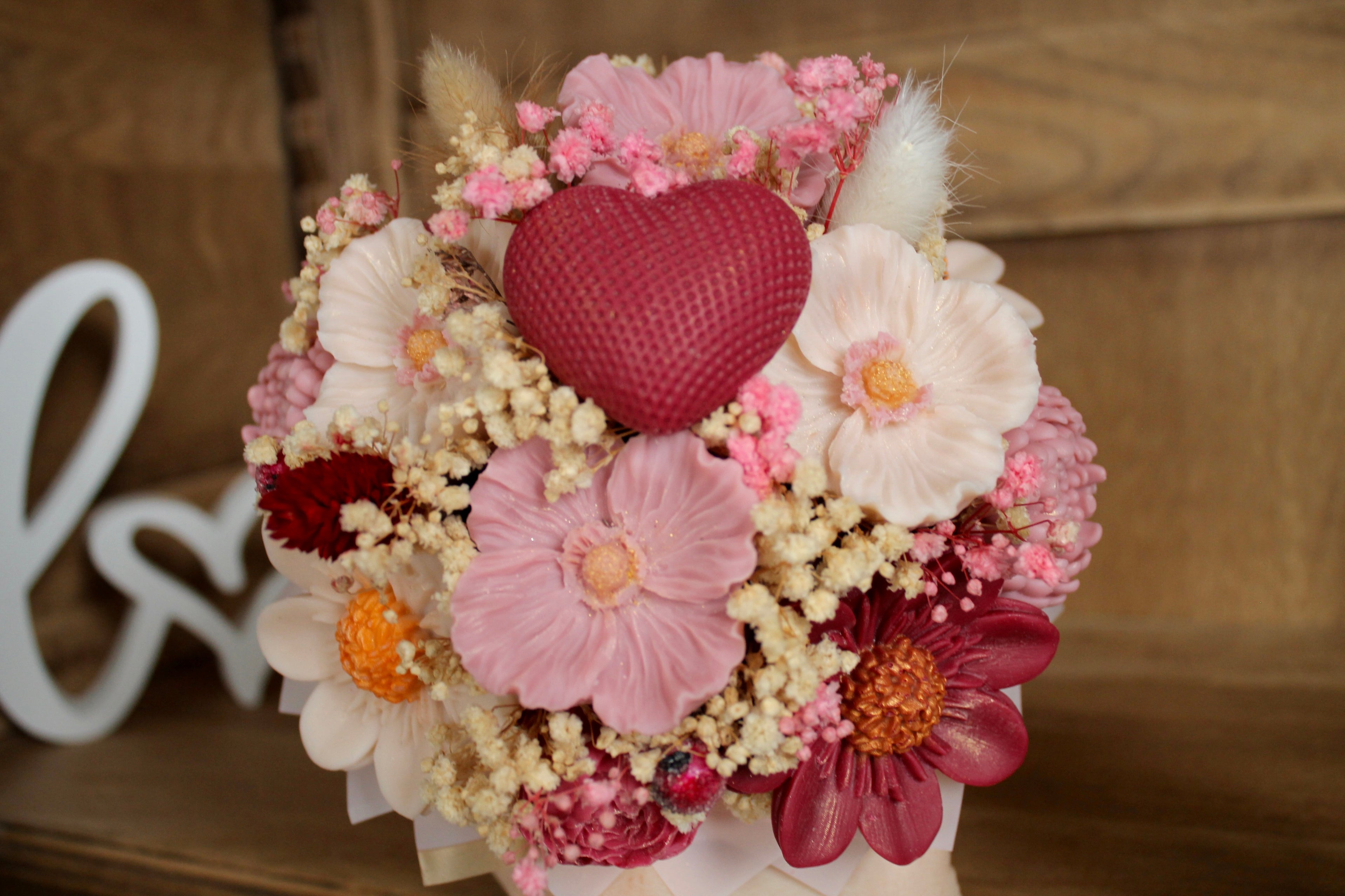 Composition artisanale de bougies en forme de fleurs avec cœur central rouge, présentée dans un élégant contenant blanc. Une création romantique idéale pour un cadeau original, une décoration de mariage ou une attention délicate pour la Saint-Valentin.