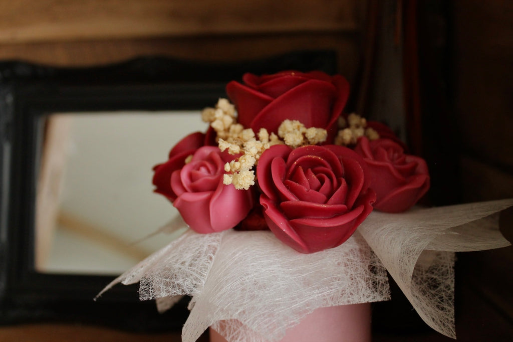 Détail d’un bouquet de roses en cire artisanales, fleurs décoratives faites main aux tons rouges et roses