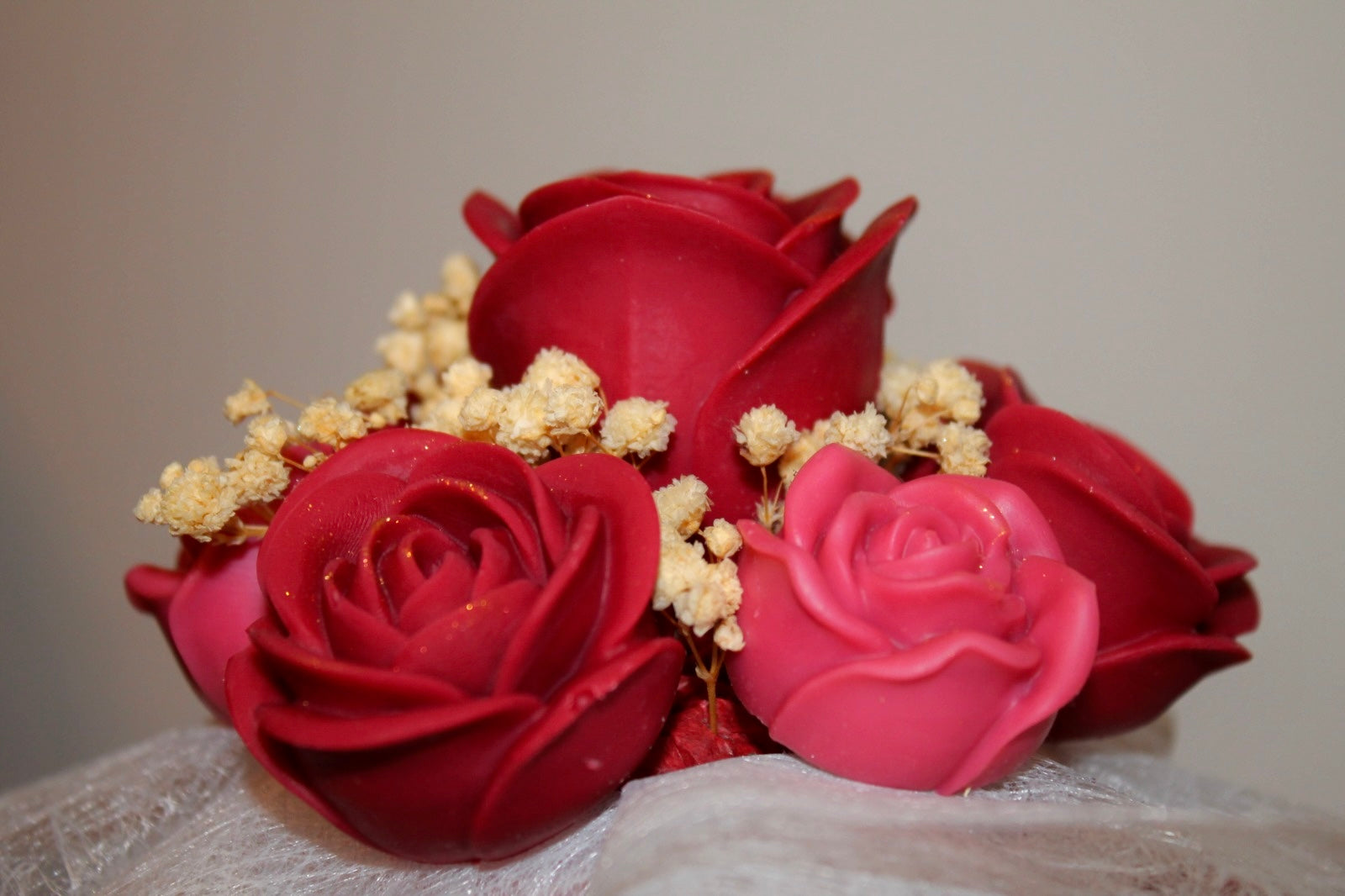Gros plan sur un bouquet de roses en cire artisanales rouges et roses, fleurs décoratives faites main