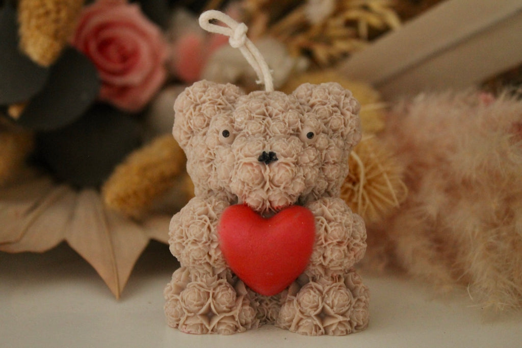 Gros plan sur un ours en cire artisanale avec cœur rouge, détail de la texture florale faite main