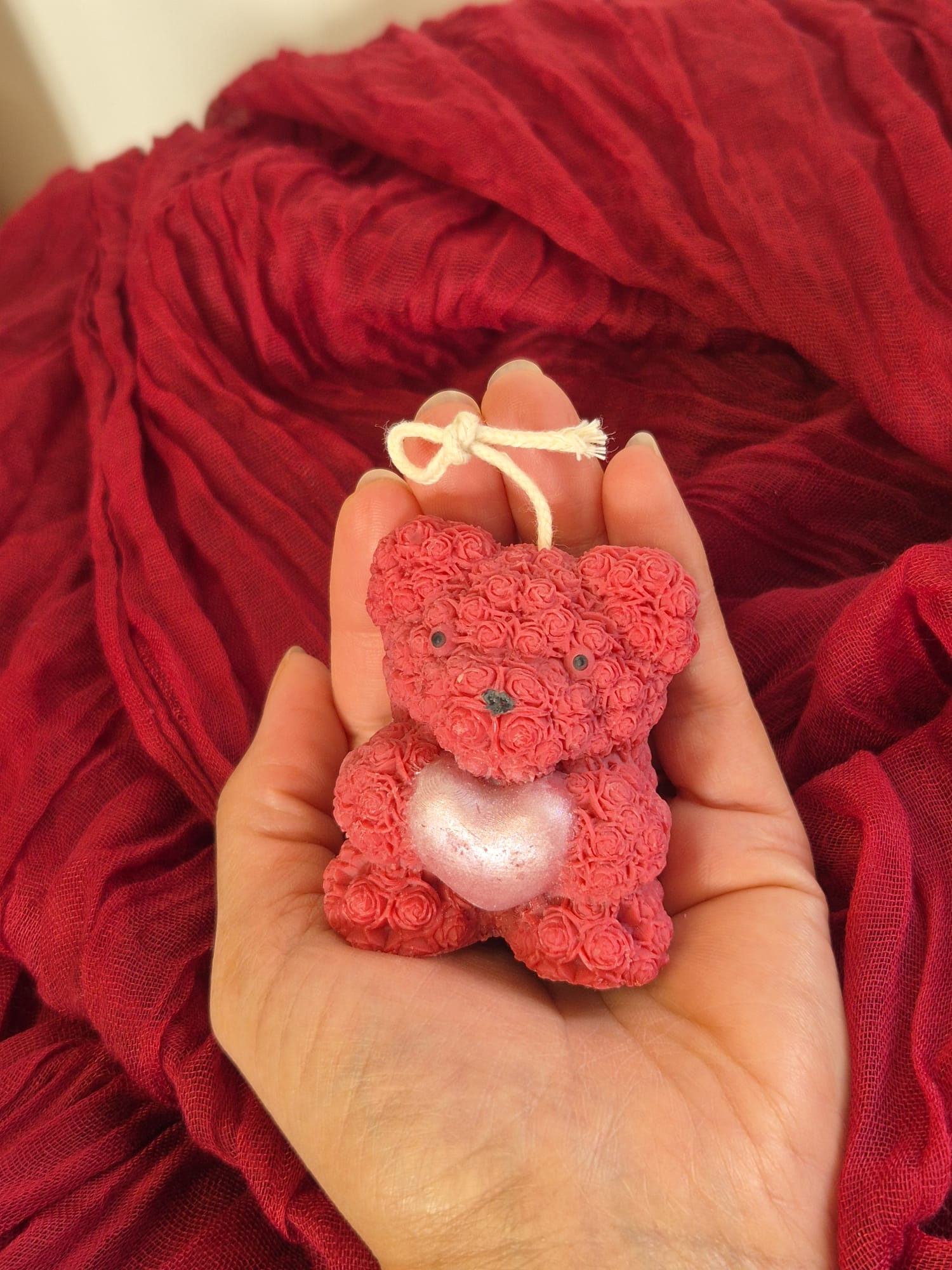 Ours en cire rouge artisanale avec cœur nacré présenté dans la main, création décorative faite main